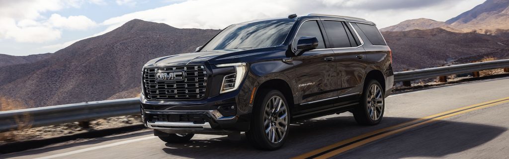 Black GMC Denali SUV driving on a mountain road.